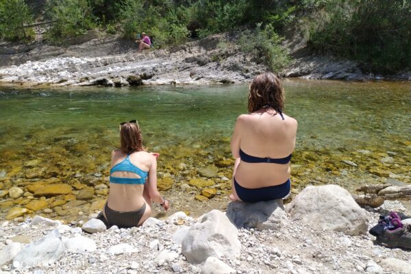 deux femmes de dos assise au bord de la rivière