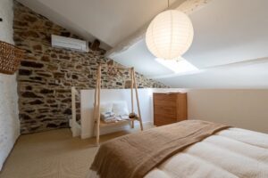 Chambre avec lit à baldaquin et mur en pierre à La Perle des Albères, demeure d'exception à Argelès-sur-Mer