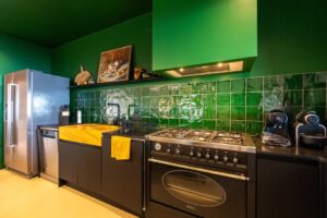 Cuisine verte avec piano de cuisson jaune à La Perle des Albères, demeure d'exception à Argelès-sur-Mer